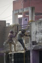 Two construction workers doing repair work of outer wall while hanging by rope. Selective focus Royalty Free Stock Photo