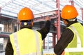 Two construction workers or foreman discussing at the site pointing at the building site Royalty Free Stock Photo