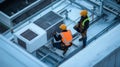 Two Construction Workers Inspecting HVAC Unit on Roof Royalty Free Stock Photo