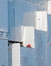 Two construction workers on orange look out from a white sheeted construction site. Royalty Free Stock Photo