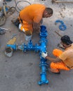 Two construction workers in orange workwear are assembling a large blue water pipe Royalty Free Stock Photo