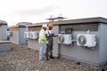 Two construction workers on roof inspecting cooling system Royalty Free Stock Photo