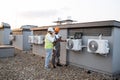 Two construction workers on roof inspecting cooling system Royalty Free Stock Photo