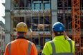 Two construction workers in safety gear operate a drone at a building site on a sunny day. Modern technology at work in Royalty Free Stock Photo
