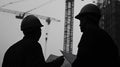 Two Construction Workers Silhouetted Against a Crane and Building Royalty Free Stock Photo