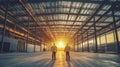 Two Construction Workers Stand in an Empty Warehouse During Sunset Royalty Free Stock Photo