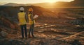 two construction workers are standing on top of a dirt hill looking at a tablet Royalty Free Stock Photo