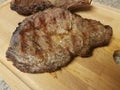 Two cooked steaks on a wood cutting board