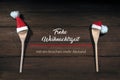 Two cooking spoons with red Santa Claus hats, German text Frohe Weihnachtszeit mit ein bisschen mehr Abstand, meaning Merry Royalty Free Stock Photo