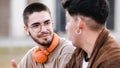 Two cool friends talking and laughing together siting outdoors