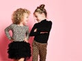 Two cool kids girls best friends sisters in leopard print clothes pants and sweater are looking at each other and walks