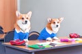 Two corgi dogs are sitting at a desk littered with school items: backpacks, markers, pencil case, notebooks.