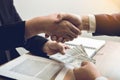 Two corporate businessmen shaking hands while one man giving money and receive cash dirty in office room with corruption concept Royalty Free Stock Photo