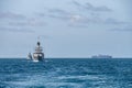 Two corvette warships sail together in the sea with container ship on the horizon Royalty Free Stock Photo