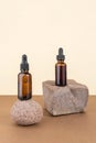 Two cosmetic brown glass bottles with pipette on stones, beige brown background. Natural Organic Spa Cosmetic concept