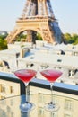 Two Cosmopolitan cocktails in traditional martini glasses with view to the Eiffel tower, Paris, France