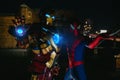 Two cosplayers stand together in images of a character Spider-Man and Iron Man against cityscape and night lights