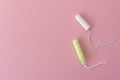 Two cotton tampons with light green applicator and without applicator on a pink background. Hygienic types of tampons.