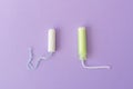 Two cotton tampons with light green applicator and without applicator on a violet background. Hygienic types of tampons.