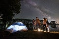 Two couple resting on lake shore near fire at night camping Royalty Free Stock Photo