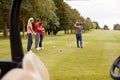 Two Couples Golfing Hitting Tee Shot Along Fairway With Driver With Buggy In Foreground Royalty Free Stock Photo