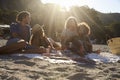 Two couples having a picnic on the beach, backlit, close up