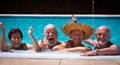 Two couples of senior people friends laughing enjoying the swimmin pool together. Bright sunlight and transparent water. Large Royalty Free Stock Photo