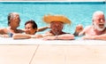 Two couples of senior people friends laughing enjoying the swimmin pool together. Bright sunlight and transparent water. Large Royalty Free Stock Photo