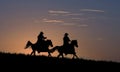 Two cowboys on horseback against dawn sky Royalty Free Stock Photo