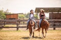 Two cowgirls riding their horses on a ranch during hot summer day Royalty Free Stock Photo