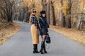 Two cozy smiling young girls walk at autumn park road Royalty Free Stock Photo