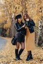 two cozy young girls walk at autumn park road an make photos Royalty Free Stock Photo