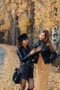 two cozy young girls walk at autumn park road an make photos Royalty Free Stock Photo