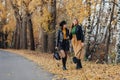 two cozy young girls walk at autumn park road an make photos Royalty Free Stock Photo