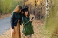 two cozy young girls walk at autumn park road an make photos Royalty Free Stock Photo