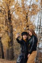 two cozy young girls walk at autumn park road an make photos Royalty Free Stock Photo