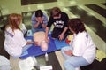 Two CPR instructors teach a family how to do CPR