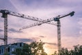 2 two cranes at apartment building construction site against sunset sky Royalty Free Stock Photo