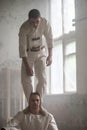 Two crazy men in straitjackets are in an abandoned clinic