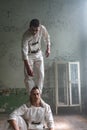 Two crazy men in straitjackets are in an abandoned clinic
