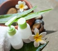 Two cream tubes and towel. Flowers and stones spa concept.