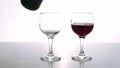 The two cristall glasses is being fulfilled with the red dry wine with rich bouquette in the restaurant bar.