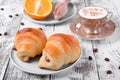 Two croissants of yeast dough on ceramic plate, freshly brewed coffee in a cup and oranges Royalty Free Stock Photo