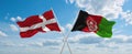 two crossed flags Afghanistan and Denmark waving in wind at cloudy sky. Concept of relationship, dialog, travelling between two