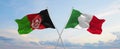 two crossed flags Afghanistan and Italy waving in wind at cloudy sky. Concept of relationship, dialog, travelling between two