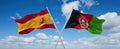two crossed flags Afghanistan and spain waving in wind at cloudy sky. Concept of relationship, dialog, travelling between two
