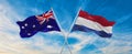 two crossed flags Australia and Netherland waving in wind at cloudy sky. Concept of relationship, dialog, travelling between two