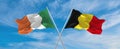 two crossed flags Belgium and Ireland waving in wind at cloudy sky. Concept of relationship, dialog, travelling between two