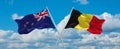 two crossed flags Belgium and New Zealand waving in wind at cloudy sky. Concept of relationship, dialog, travelling between two