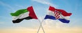 two crossed flags Croatia and United Arab Emirates waving in wind at cloudy sky. Concept of relationship, dialog, travelling